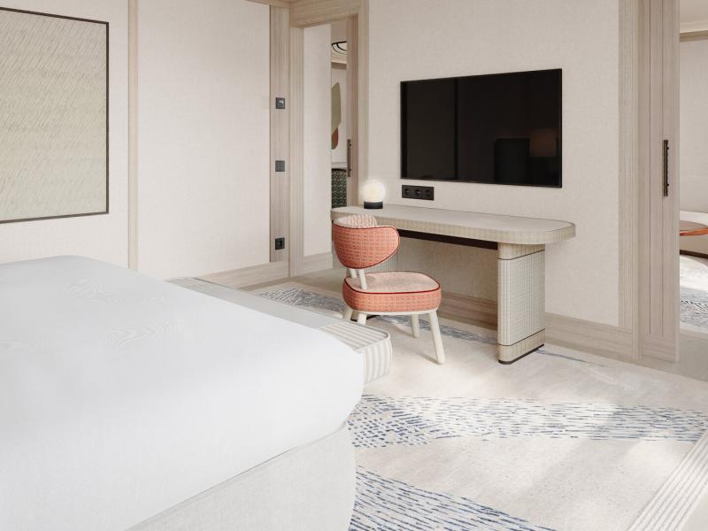 Hotel Miramar Barcelona refined guest room features a sleek wall‑mounted TV, minimalist desk, and textured area rug, complemented by soft white interiors with accents of blush pink, pale gray, and warm wood.
