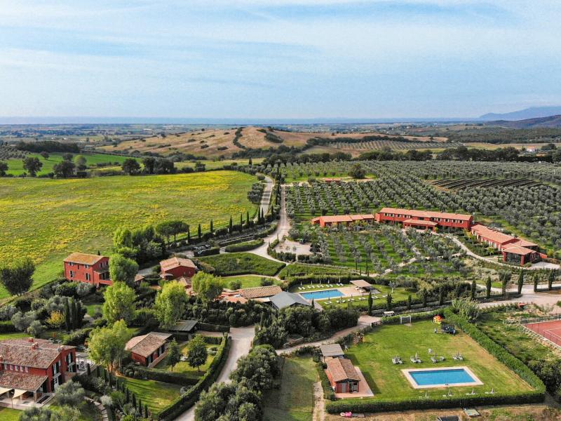 The sweeping countryside estate of Locanda Rossa unfolds with manicured gardens, tree‑lined driveways, and classic villas accented by lush greens, warm terracotta roofs, and golden fields.