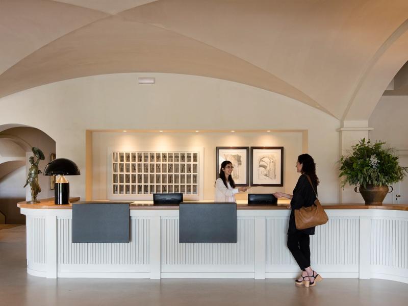 Hotel Peralada’s elegant lobby features curved cream archways, clean white paneling, and accents of soft beige and green for a welcoming arrival experience.