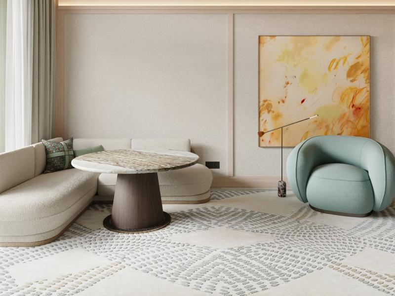 Hotel Miramar Barcelona suite sitting area features a sculptural round table, curved lounge seating, and soft textured flooring, accented by sage green, warm beige, and muted stone tones.