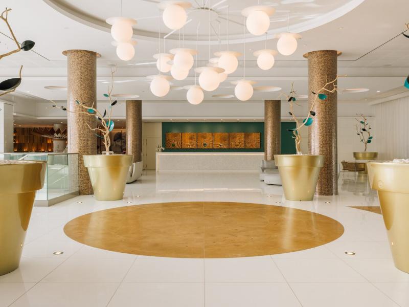 EPIC SANA Algarve elegant, light-filled lobby showcases sculptural white pendants, gleaming gold accents, and soft teal details set against polished ivory stone.