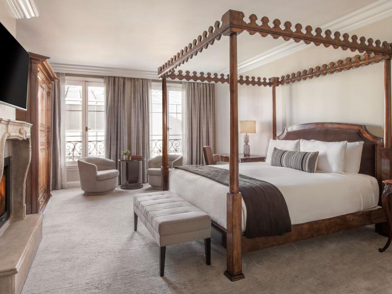 This exquisitely appointed Premier Guestroom features a majestic four-poster bed, glowing fireplace, and refined sitting area awash in creamy white, silvery gray, and richly stained walnut.