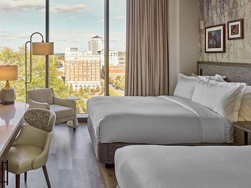 Modern guestrooms pair comfort and style with floor-to-ceiling windows showcasing views of the surrounding city.