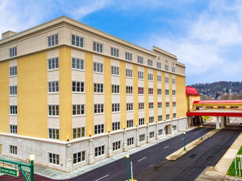 Showcasing a refined cream façade, striking red architectural accents, and a private porte cochère, the Valley Tower at French Lick Springs Hotel offers polished luxury, seamless arrivals, and elevated resort sophistication.
