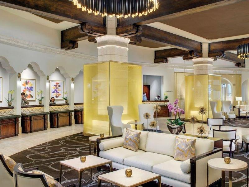 Green Valley Ranch Resort Spa Casino worldly lobby featuring plush white seating and bold geometric carpeting, highlighted by golden accent panels and sleek black chandeliers.