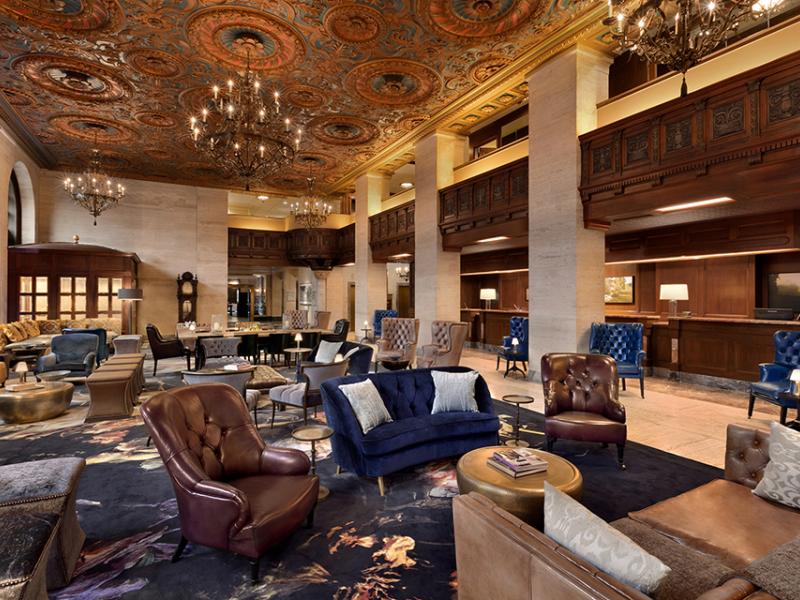 HOTEL DU PONT luxurious lobby blends plush seating and carved wood details with sophisticated navy and copper accents under an ornate ceiling.