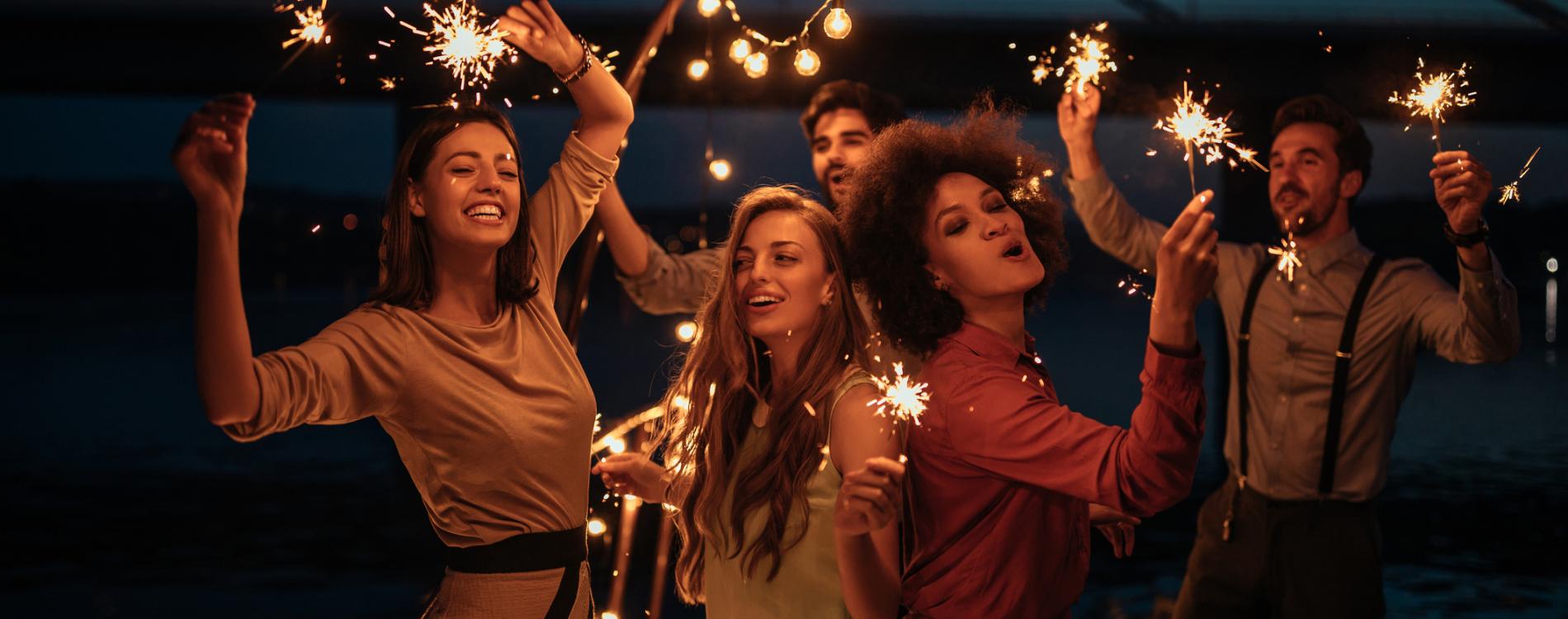 People dancing in a party with sparklers.