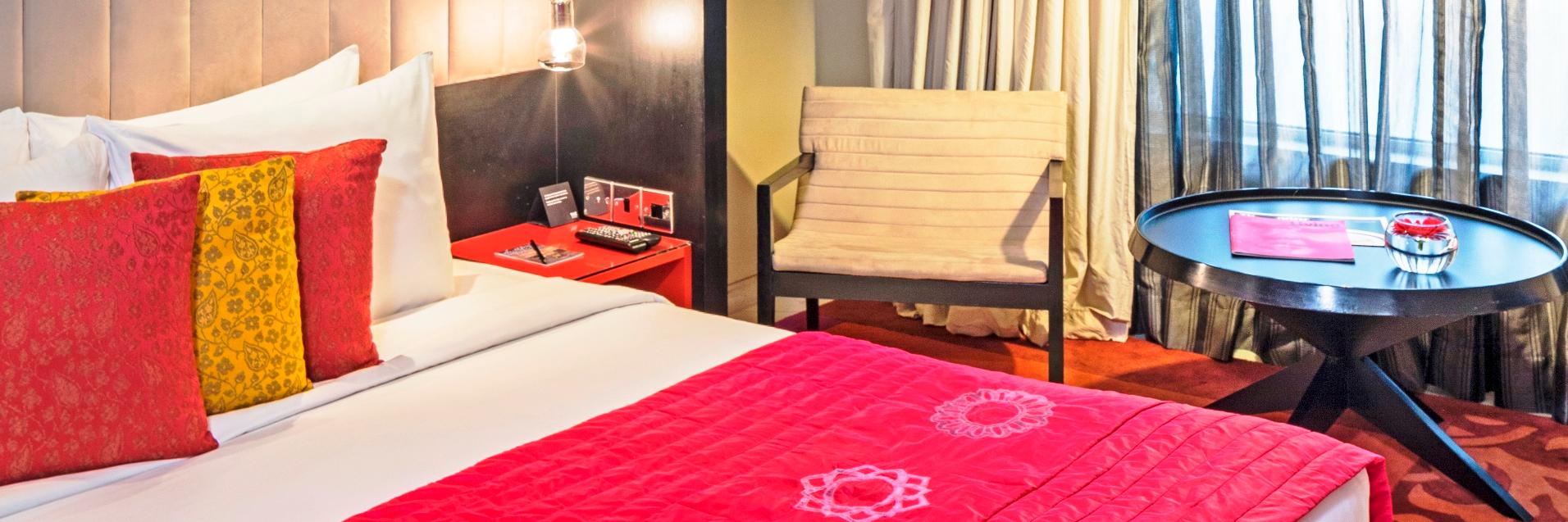 guest room with red bedspread, white arm chair, white curtains, large windows, the park kolkata accommodations