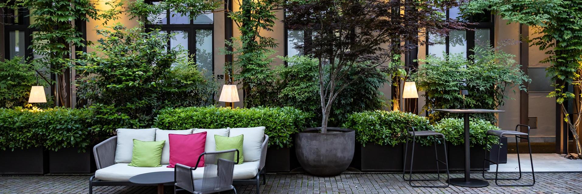 Tranquil Garden courtyard with seating and umbrellas Savona 18 Suites